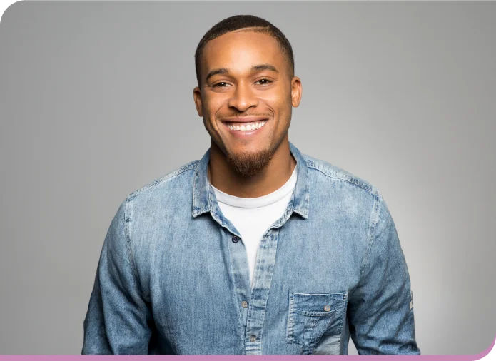Smiling man in a light blue denim shirt against a gray studio background.